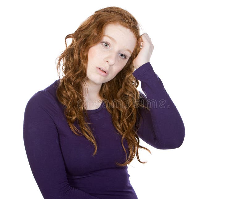 Une adolescente rousse mignonne se gratte la tête photo stock