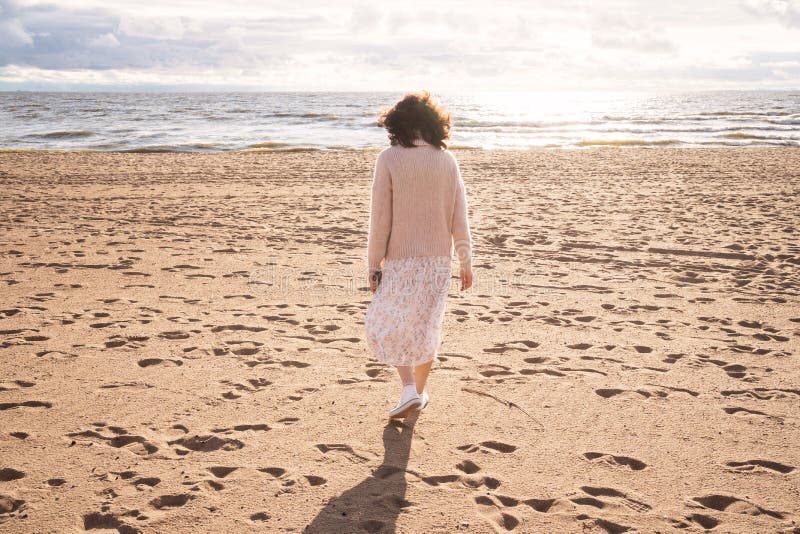 La unidad del hombre con la naturaleza. una niña camina a lo largo de una playa de arena junto al mar. una chica solitaria camina imágenes de archivo libres de regalías