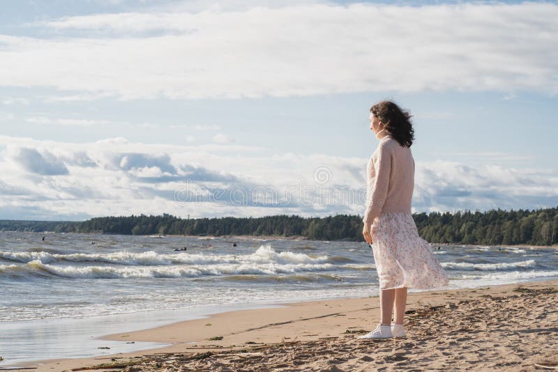 La unidad del hombre con la naturaleza. una niña camina a lo largo de una playa de arena junto al mar. una chica solitaria camina fotografía de archivo libre de regalías