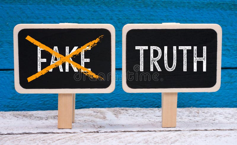 The truth - no fake - two little chalkboards with text on blue wooden background. The truth - no fake - two little chalkboards with text on blue wooden background