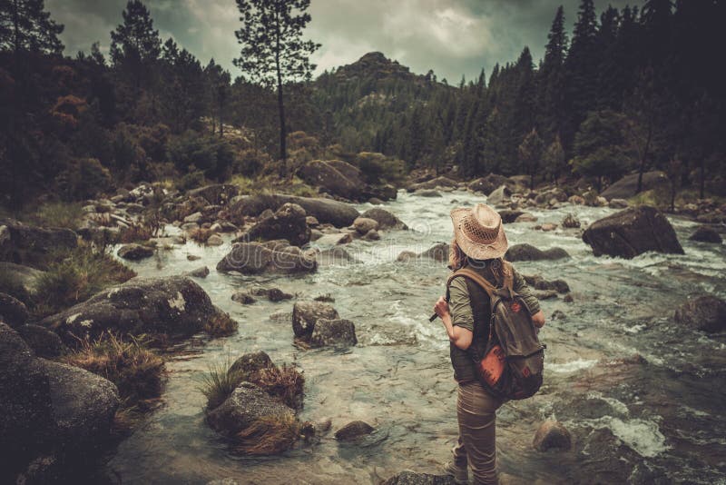 La viandante della donna che gode dei paesaggi stupefacenti si avvicina al fiume selvaggio della montagna fotografia stock libera da diritti La viandante della donna che gode dei paesaggi stupefacenti si avvicina al fiume selvaggio della montagna fotografia stock libera da diritti