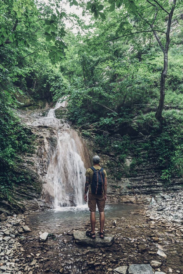 La viandante ha raggiunto la destinazione e vista godere della cascata e della natura non rovinata di bellezza Concetto di avvent fotografia stock La viandante ha raggiunto la destinazione e vista godere della cascata e della natura non rovinata di bellezza Concetto di avvent fotografia stock
