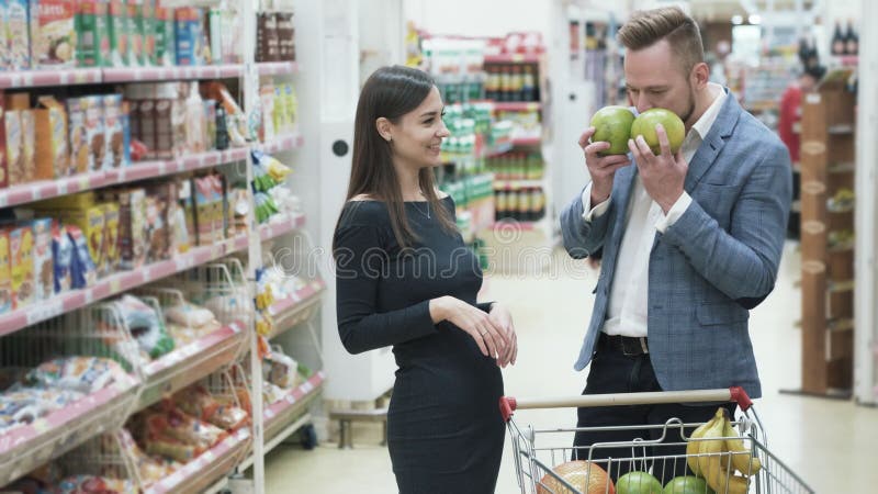 La vidéo positive de jeunes couples, femme fait le visage drôle avec des fruits au supermarché banque de vidéos