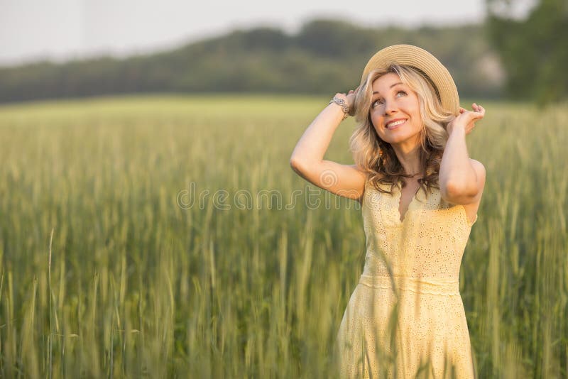 La vie rurale et rurale Marche par la jeune femme blonde de pr? dans un chapeau ?t? photographie stock libre de droits La vie rurale et rurale Marche par la jeune femme blonde de pr? dans un chapeau ?t? photographie stock libre de droits