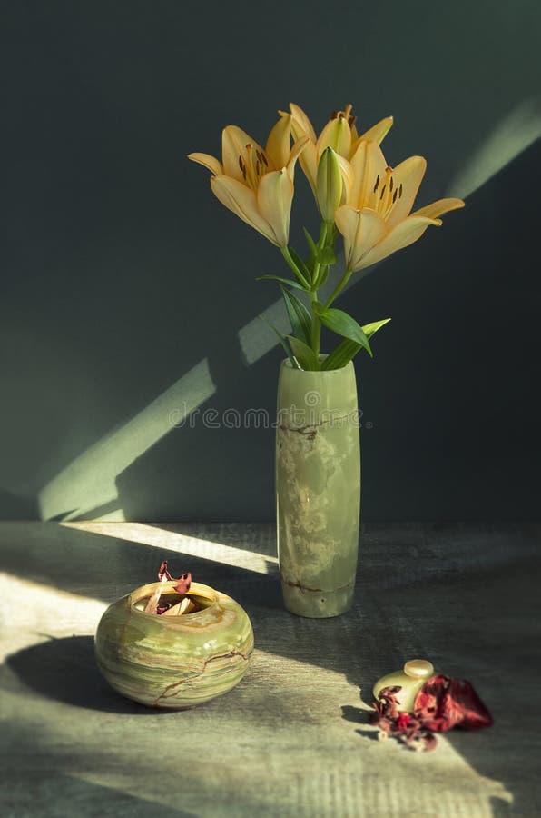 La vie toujours avec des lis dans un vase vert fait en pierre naturelle photographie stock La vie toujours avec des lis dans un vase vert fait en pierre naturelle photographie stock