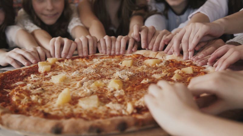 La vista de los fingeres del ` s de los niños que se mueven síncrono y ayuna a la pizza en un centro almacen de video