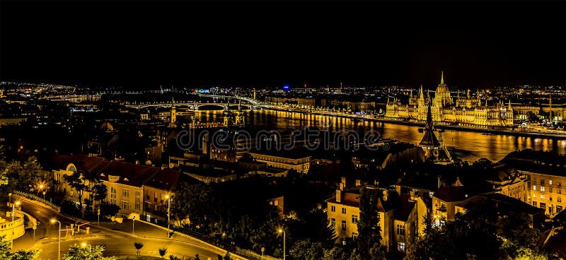 The view from the Fisherman`s Bastion towards the Parliament Building and Margaret Island across the River Danube in Budapest at night during the summertime. The view from the Fisherman`s Bastion towards the Parliament Building and Margaret Island across the River Danube in Budapest at night during the summertime