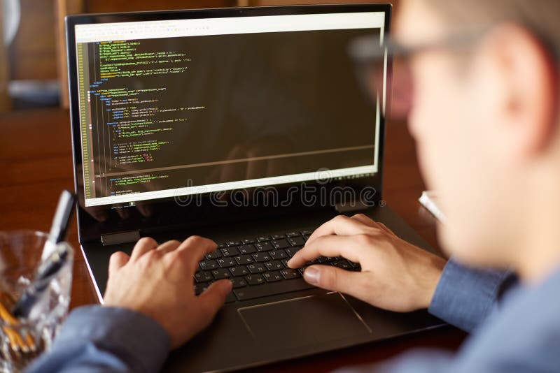 La vista posteriore sopra la spalla ha sparato del programmatore dello sviluppatore con il computer portatile Programmi il codice fotografia stock libera da diritti La vista posteriore sopra la spalla ha sparato del programmatore dello sviluppatore con il computer portatile Programmi il codice fotografia stock libera da diritti