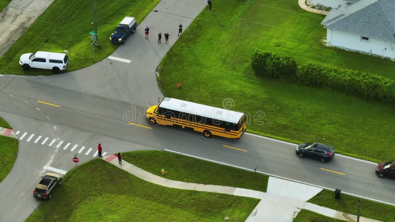 La vista principale del bus scolastico giallo americano che raccoglie i bambini alla fermata della strada rurale per le lezioni al