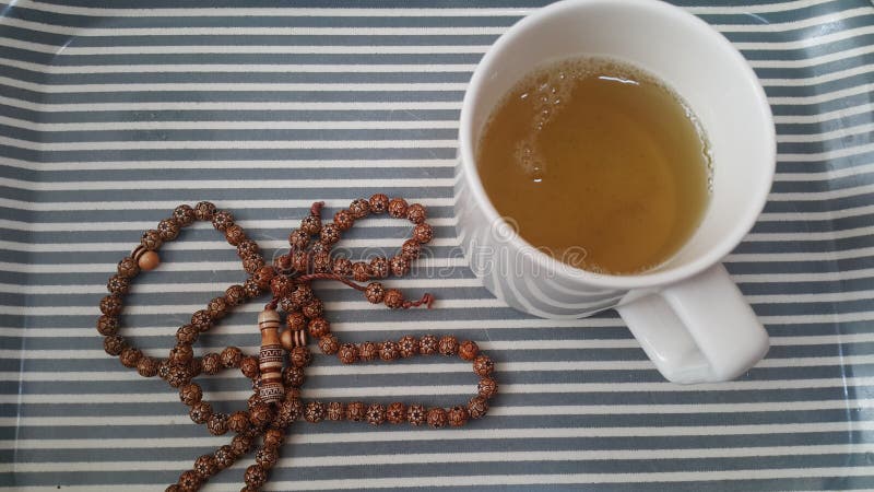La vista superior del té verde en una taza con las gotas de rezo o el rosario colocó en una bandeja imagen de archivo La vista superior del té verde en una taza con las gotas de rezo o el rosario colocó en una bandeja imagen de archivo