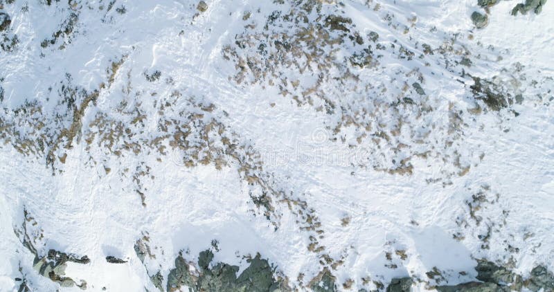 La vista superiore aerea sopraelevata sopra la montagna nevosa dell'inverno oscilla Montagne rocciose coperte in ghiacciaio del g