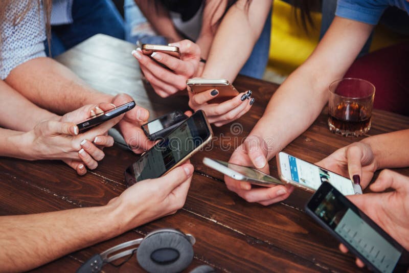 Top view hands circle using phone in cafe - Multiracial friends mobile addicted interior scene from above - Wifi connected people in bar table meeting - Concept of teamwork. Top view hands circle using phone in cafe - Multiracial friends mobile addicted interior scene from above - Wifi connected people in bar table meeting - Concept of teamwork.