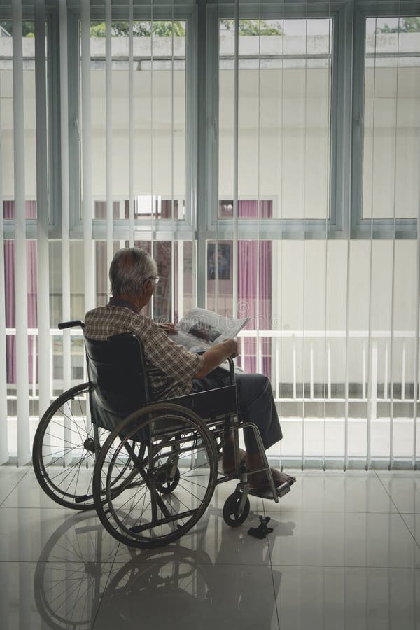 La vue arrière de l'homme supérieur handicapé lit un journal photos stock La vue arrière de l'homme supérieur handicapé lit un journal photos stock