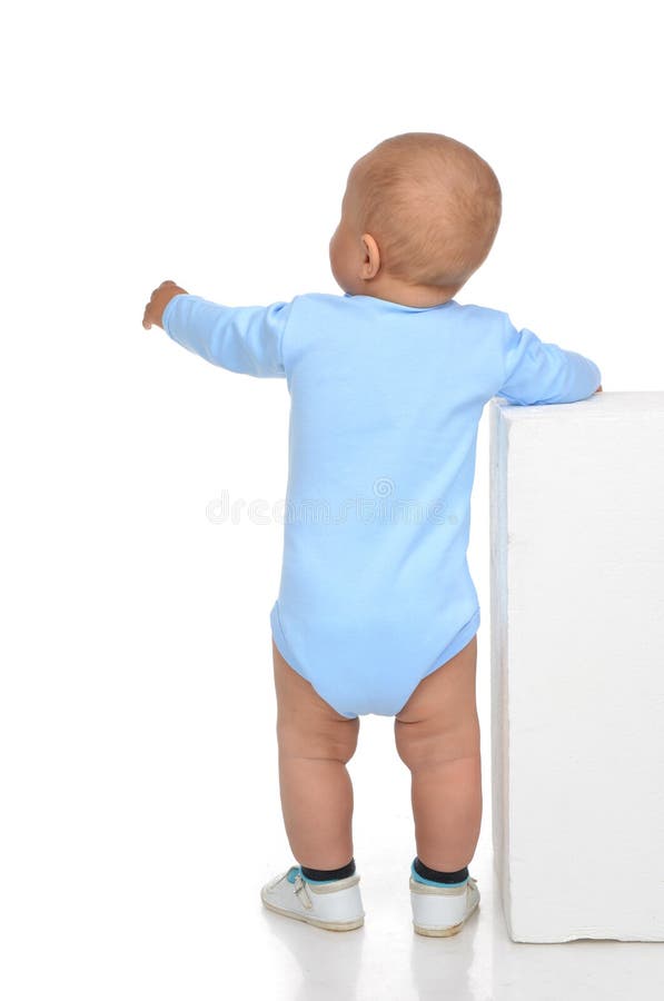 La vue arrière du plein corps caucasien un bébé garçon infantile d'an font ses premiers pas