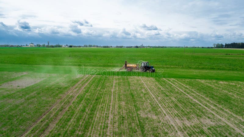 La vue aérienne, agriculteur sur un tracteur avec un pulvérisateur fait l'engrais pour de jeunes légumes images libres de droits La vue aérienne, agriculteur sur un tracteur avec un pulvérisateur fait l'engrais pour de jeunes légumes images libres de droits
