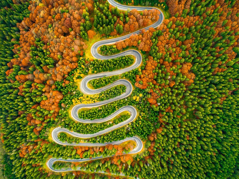 La vue aérienne de la route d'enroulement par l'automne a coloré la forêt photos stock