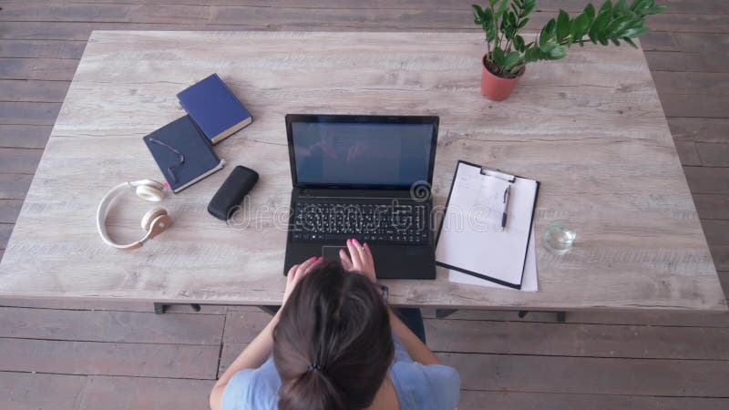 La vue aérienne du texte de dactylographie de fille d'indépendant sur le clavier d'ordinateur portable et écrit des notes dans le