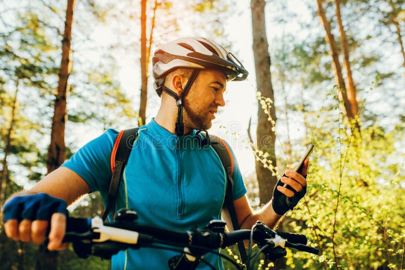 La vue de côté inférieure et du cycliste sur le vélo utilisant le navigateur au téléphone intelligent, explorer la carte et la re images libres de droits La vue de côté inférieure et du cycliste sur le vélo utilisant le navigateur au téléphone intelligent, explorer la carte et la re images libres de droits