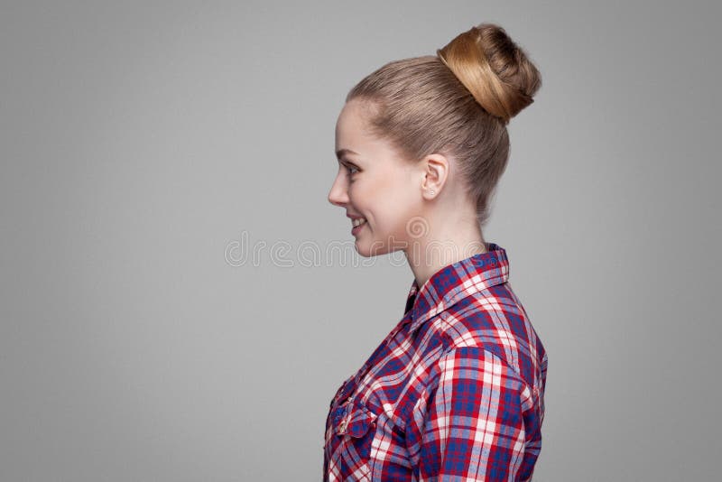 La vue de côté de profil de la belle fille blonde dans la chemise à carreaux rouge et rose, a rassemblé la position de coiffure d image libre de droits La vue de côté de profil de la belle fille blonde dans la chemise à carreaux rouge et rose, a rassemblé la position de coiffure d image libre de droits