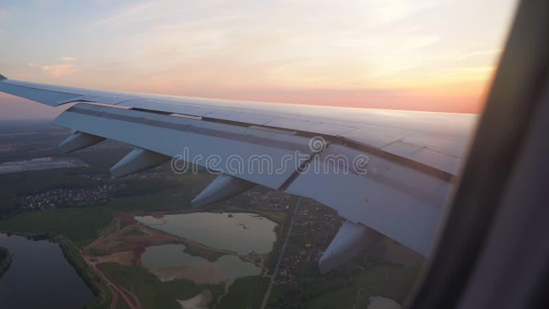 La vue du coucher du soleil de la fenêtre de l'avion aile au soleil À trajectoire aérienne