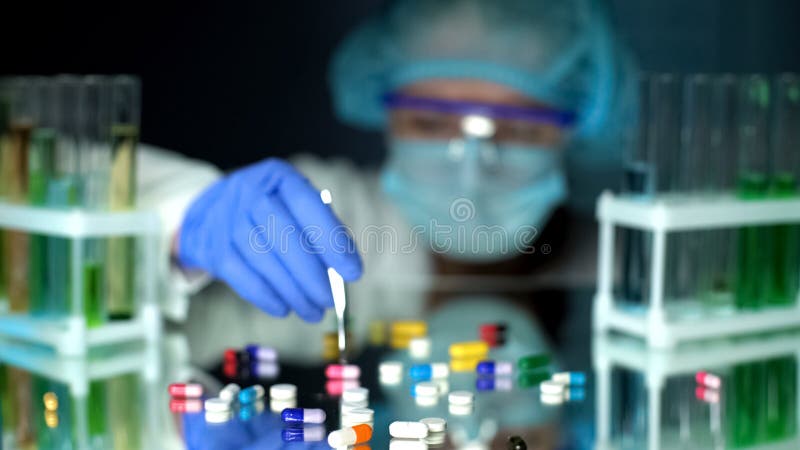 Lab assistant analyzing medication capsules, counterfeit pharmaceuticals, study stock images Lab assistant analyzing medication capsules, counterfeit pharmaceuticals, study stock images