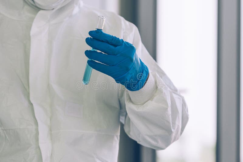 Lab Technician in Personal protective equipment  PPE suit holding test tube of  Vaccines testing of Virus in Laboratory