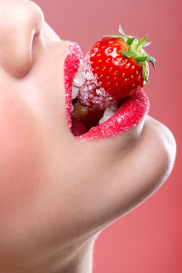 Labios rojos femeninos hermosos, llenos con el azúcar granulado, mordiendo una fresa fotografía de archivo libre de regalías Labios rojos femeninos hermosos, llenos con el azúcar granulado, mordiendo una fresa fotografía de archivo libre de regalías