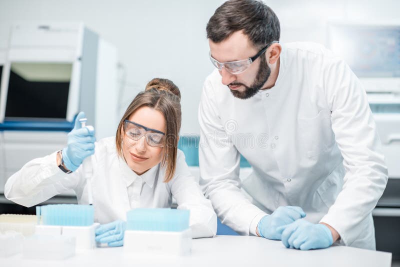 Laboranter som arbetar i det medicinska laboratoriumet royaltyfri bild Laboranter som arbetar i det medicinska laboratoriumet royaltyfri bild