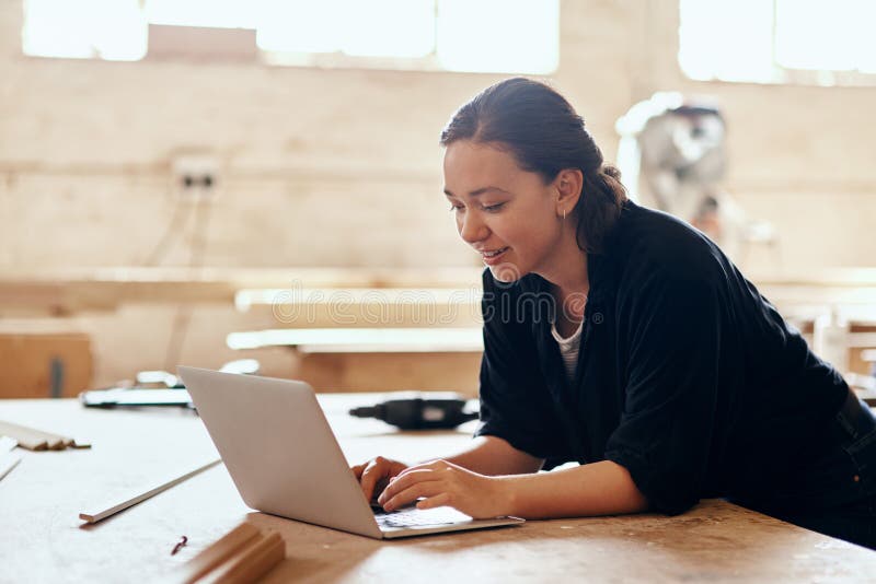 Laboratorio carpentiere e donna con laptop per ricerche o informazioni sulla punta del legno. piccola impresa immagine stock