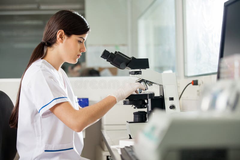 Laboratorio femminile di Using Microscope In dello scienziato immagini stock