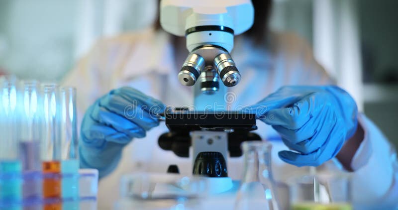 Laboratory technician places sample under microscope stock video footage
