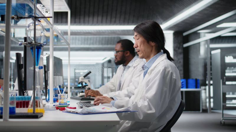 Laboratory technician uses computer app, doing research into human health stock footage