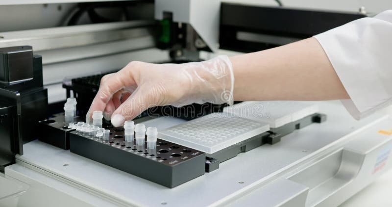 Laboratory technician wearing gloves placing microplate into automated machine for scientific analysis. Modern laboratory setup stock footage