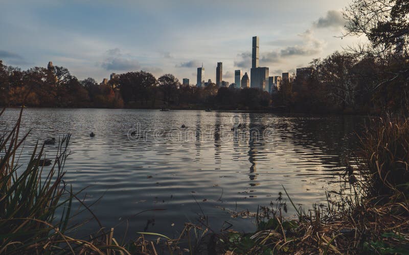 Lac central park avec l'horizon de New York derrière pendant le jour nuageux d'automne en retard photographie stock libre de droits Lac central park avec l'horizon de New York derrière pendant le jour nuageux d'automne en retard photographie stock libre de droits
