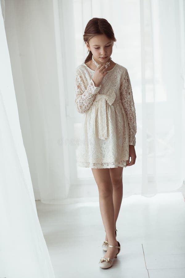 Fashion 7 years old model dressed in ivory lace dress pastel tone