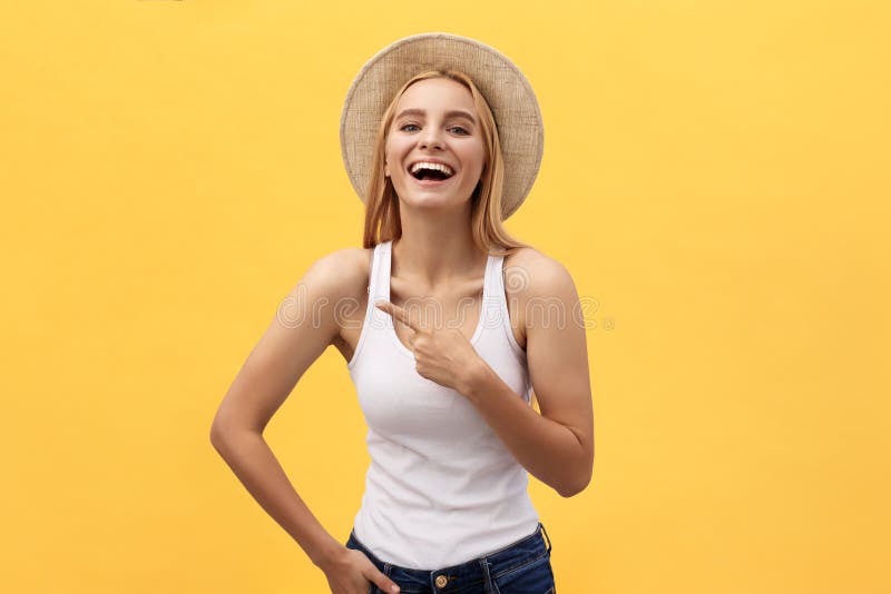 Laughing young beautiful woman in t-shirt looking and pointing away with finger over yellow background. Laughing young beautiful woman in t-shirt looking and pointing away with finger over yellow background.