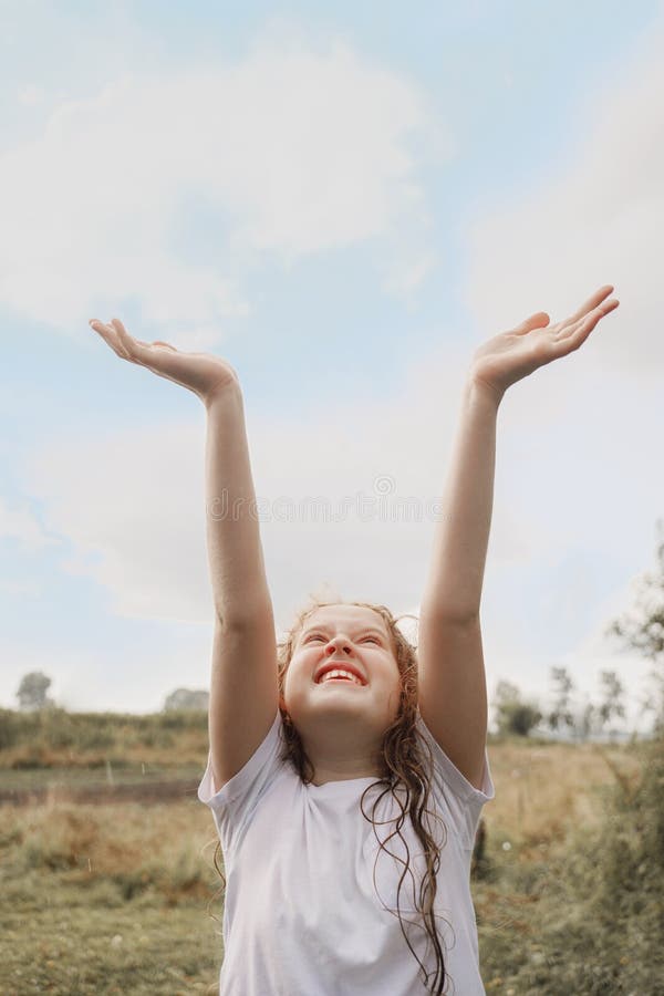 Laughing child spread its arms and catches raindrops and sunrayses. Freedom, happy childhood, healthy lifestyle concept. Laughing child spread its arms and catches raindrops and sunrayses. Freedom, happy childhood, healthy lifestyle concept