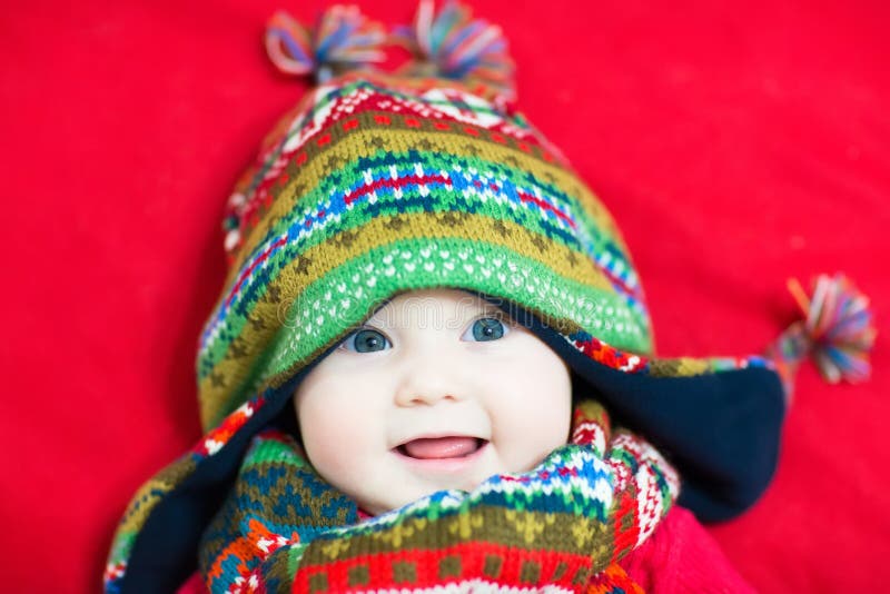 Lachendes glückliches Baby in einer bunten Strickmütze und in einem Schal stockbild