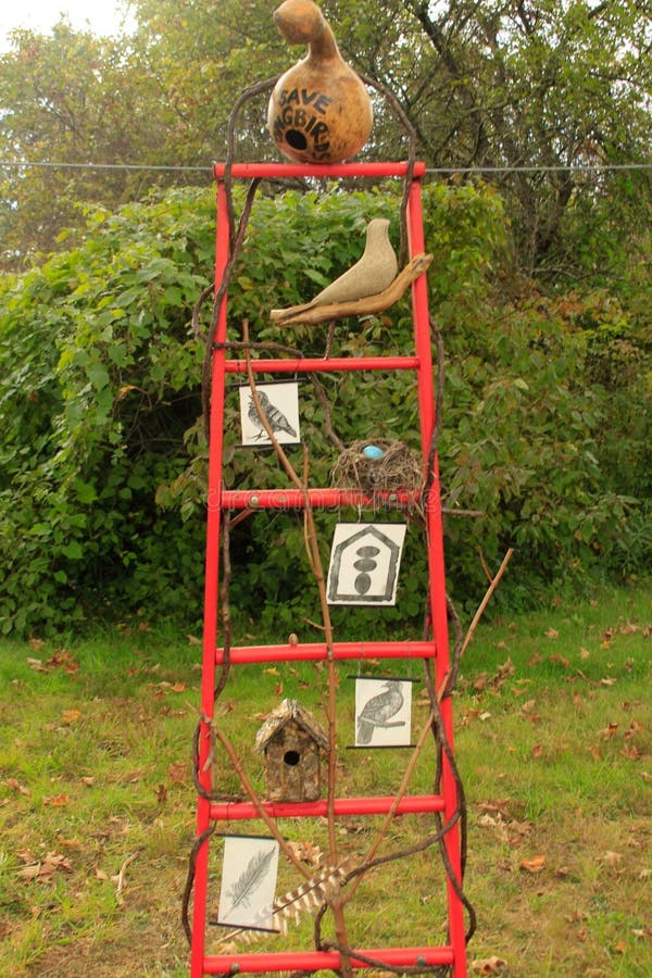 Ladder art sculpture display on a red metal round ladder with a gourd as a bird house which reads save the songbirds, and other birds, a nest with robins eggs, and pictures of birds and egggs, bird house. Ladder art sculpture display on a red metal round ladder with a gourd as a bird house which reads save the songbirds, and other birds, a nest with robins eggs, and pictures of birds and egggs, bird house.