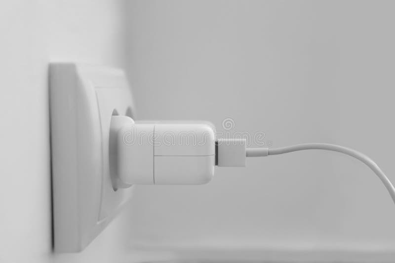 Charging adapter plugged in electric socket, closeup. Charging adapter plugged in electric socket, closeup