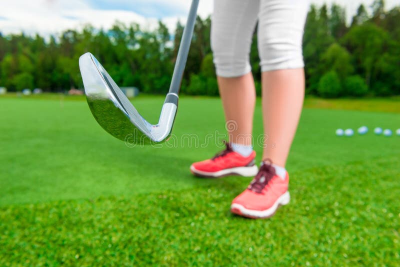 Ladies feet and golf putter on the grass