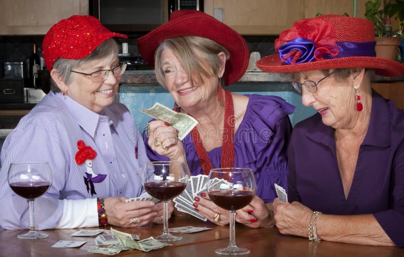 Ladies wearing red hats playing a hand of cards. Ladies wearing red hats playing a hand of cards