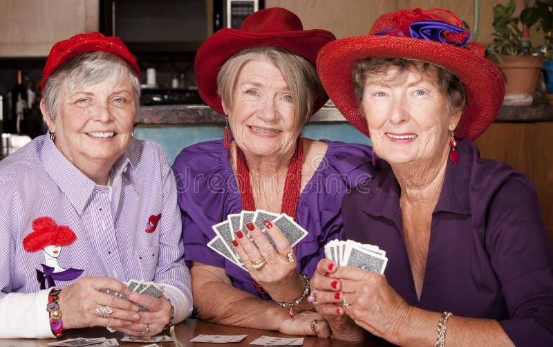 Ladies wearing red hats playing a hand of cards. Ladies wearing red hats playing a hand of cards