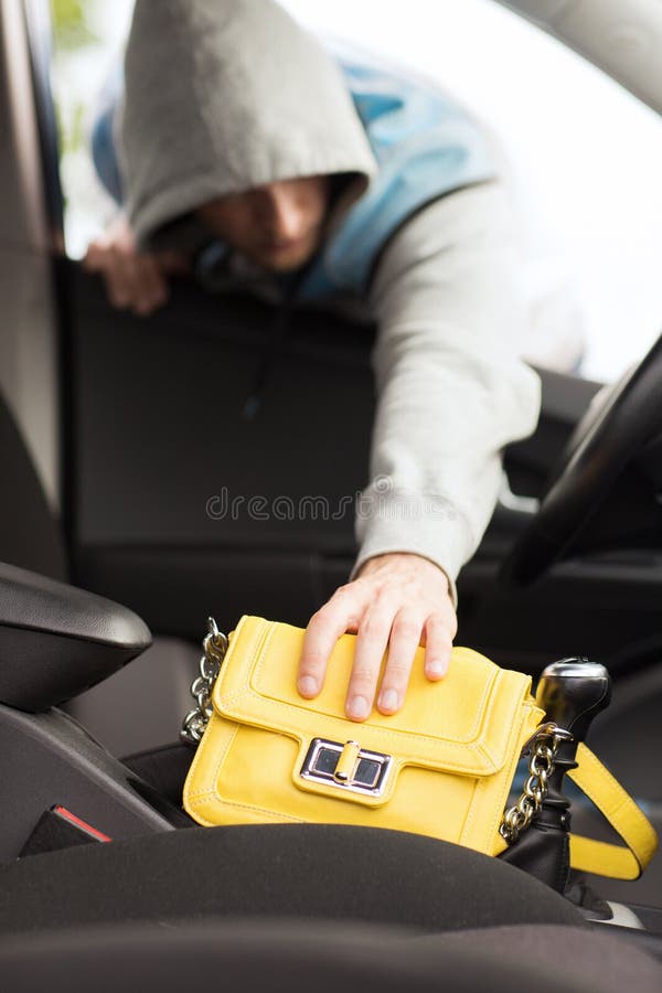 Transportation, crime and ownership concept - thief stealing bag from the car. Transportation, crime and ownership concept - thief stealing bag from the car