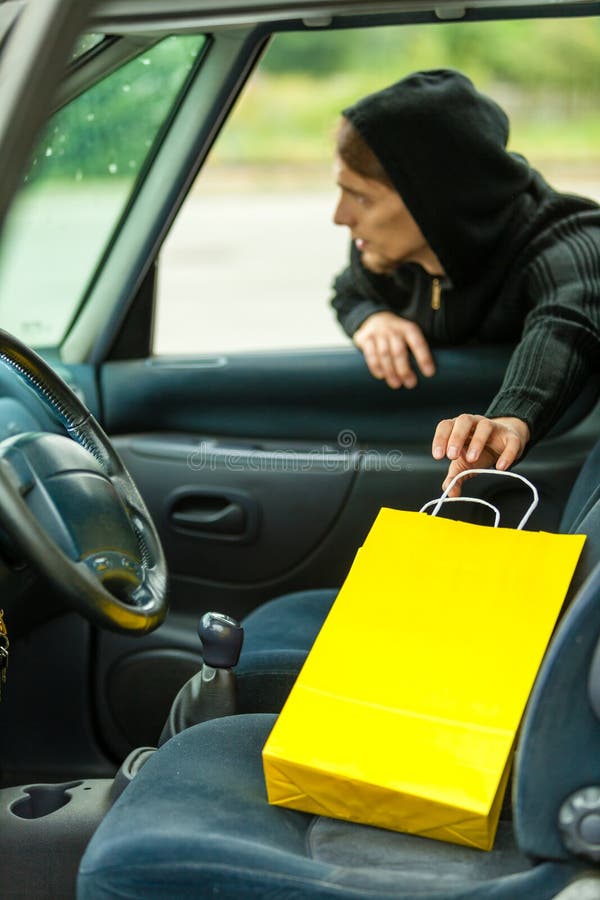 Ladro che ruba sacchetto della spesa dall'automobile immagine stock libera da diritti Ladro che ruba sacchetto della spesa dall'automobile immagine stock libera da diritti