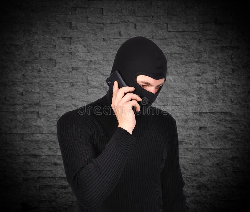 Robber talking on phone on a green wall background. Robber talking on phone on a green wall background