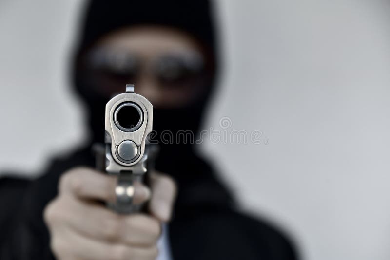Ladrón criminal con apuntar el arma, chico malo en la capilla que sostiene la pistola