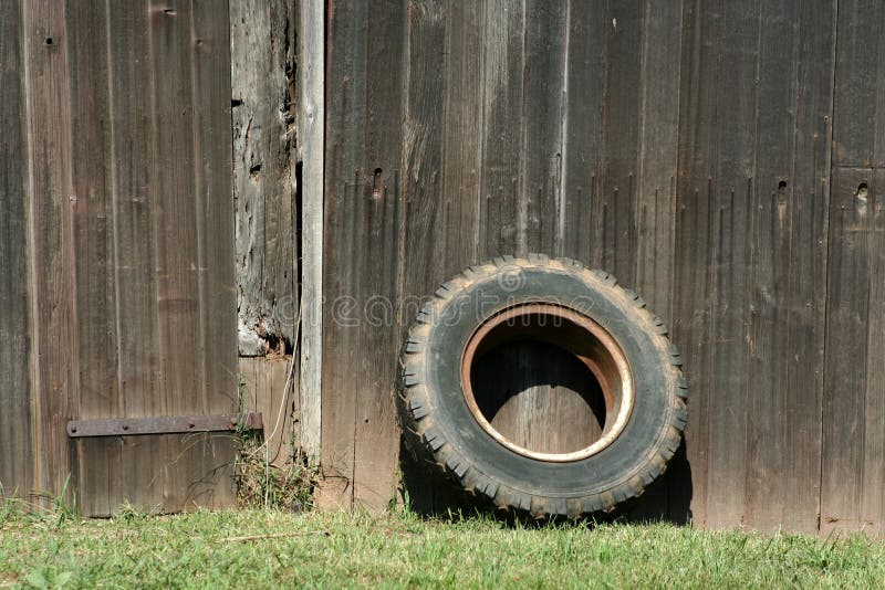 A Tire leaning on a old barn. A Tire leaning on a old barn