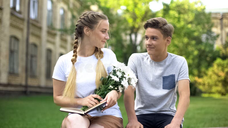 Lady with bouquet of flowers looking with love at boyfriend, romantic present