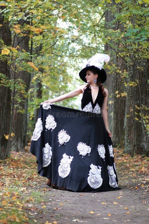 Lady in retro dress walking in trees alley